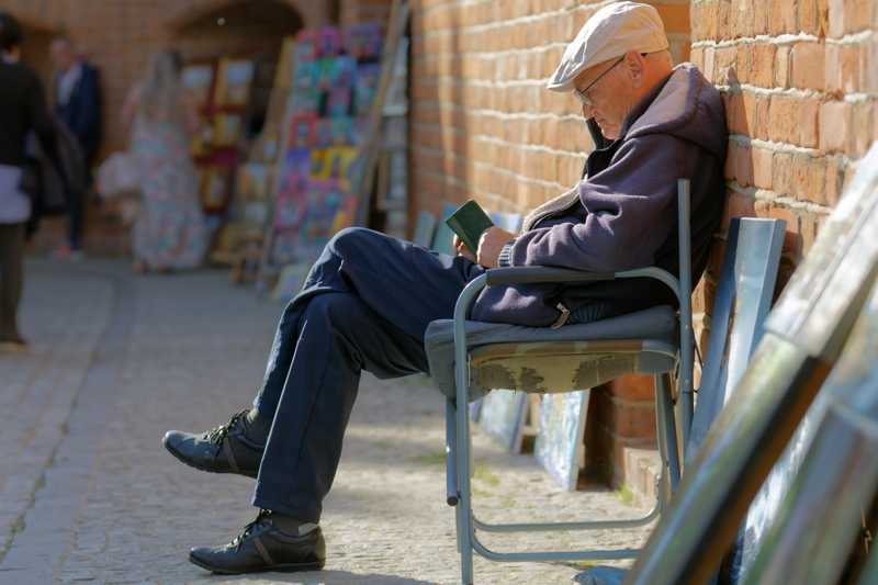 8 - An older man relaxing on a chair against a brick wall